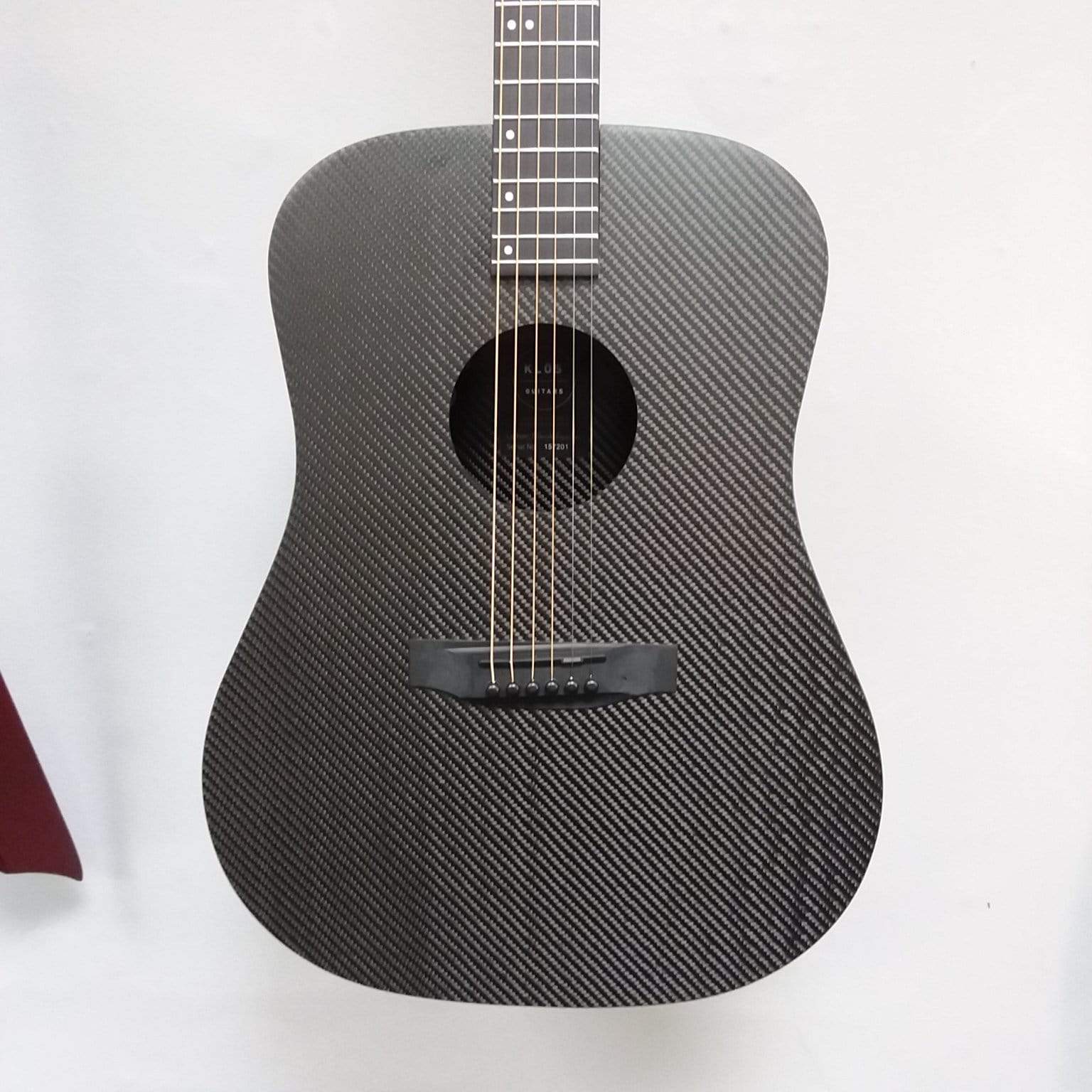 Klos Full Carbon Deluxe Acoustic Electric Guitar with visible sound hole and strings, highlighting its durable carbon fiber body and preamp feature.