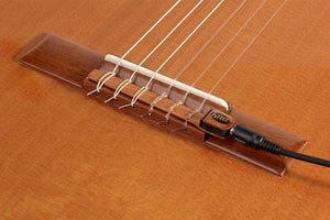 Close-up of KNA NG-1 Piezo Pick-up installed on a classical guitar's tie bar, showcasing its secure fit and elegant mahogany casing.