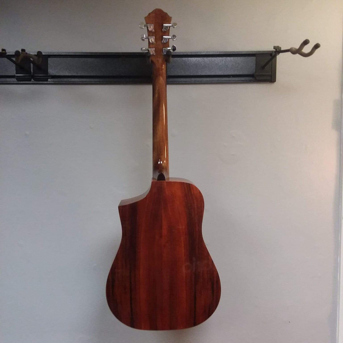 Michael Kelly Forte Koa Jr. travel guitar mounted on a wall, showcasing its koa wood body and compact design.