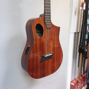 Michael Kelly Forte Koa Jr. travel guitar displayed on a wall, highlighting its koa wood body and compact design.