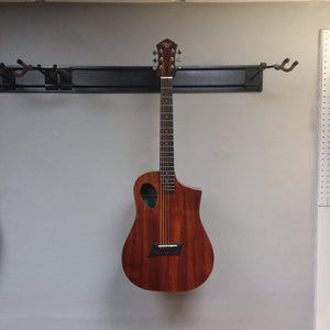 Michael Kelly Forte Koa Jr. guitar mounted on a wall, highlighting its compact size and top bracing design.