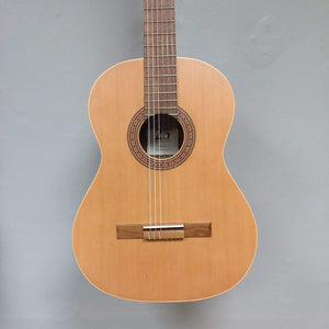 Ortega Nylon String Guitar R189SN-25TH with gig bag, featuring a solid cedar top and Granadillo back, displayed on a wall.