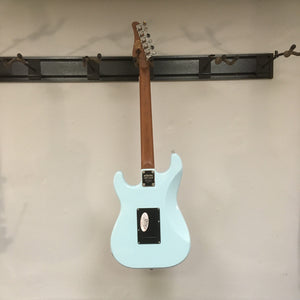 Schecter Nick Johnston Traditional Atomic Frost Electric Guitar mounted on a wall, showcasing its classic design and modern features.