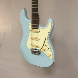 Schecter Nick Johnston Traditional Atomic Frost Electric Guitar mounted on a wall, showcasing its classic design and modern features.