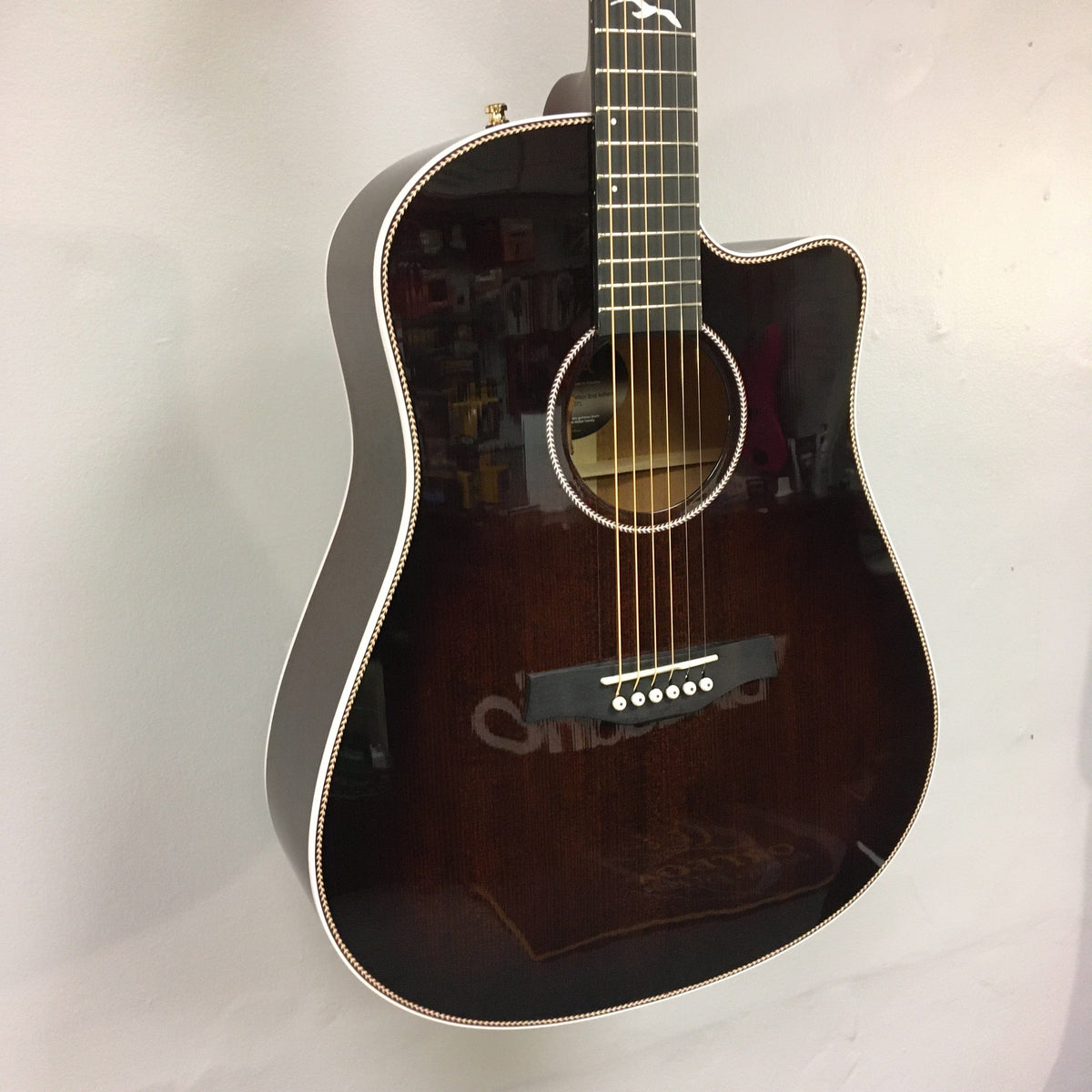 Seagull Artist Peppino Signature Acoustic Guitar displayed on a wall, showcasing its solid spruce top and mahogany neck, back, and sides.